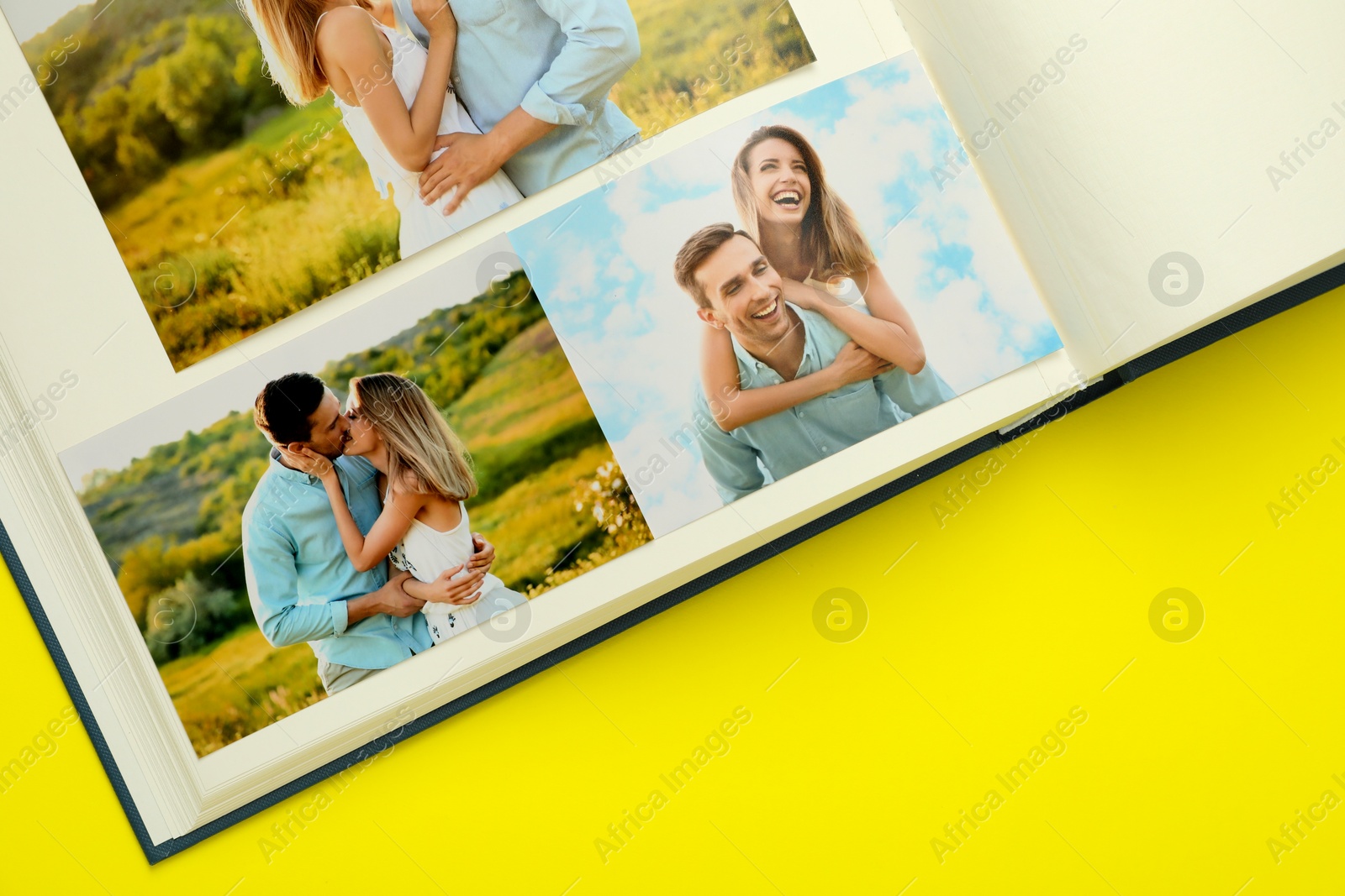 Photo of Open photo album with different photos on yellow background, top view