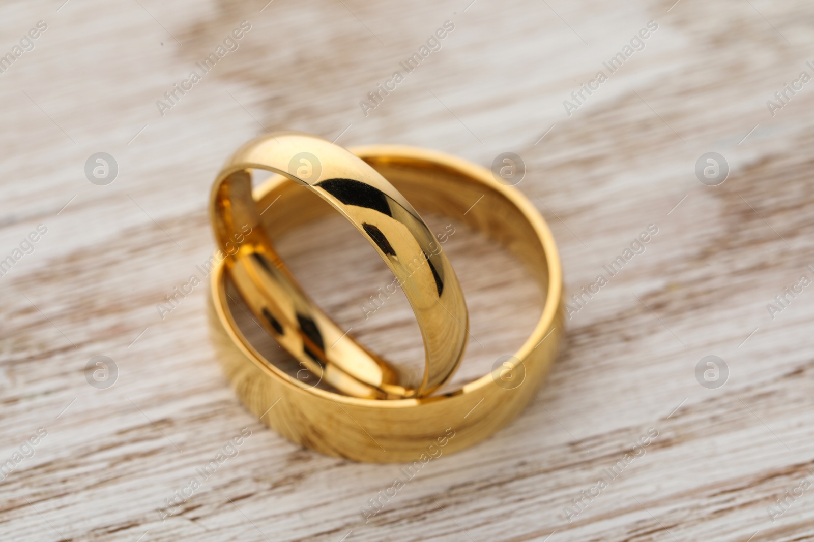 Photo of Beautiful golden wedding rings on wooden table, closeup