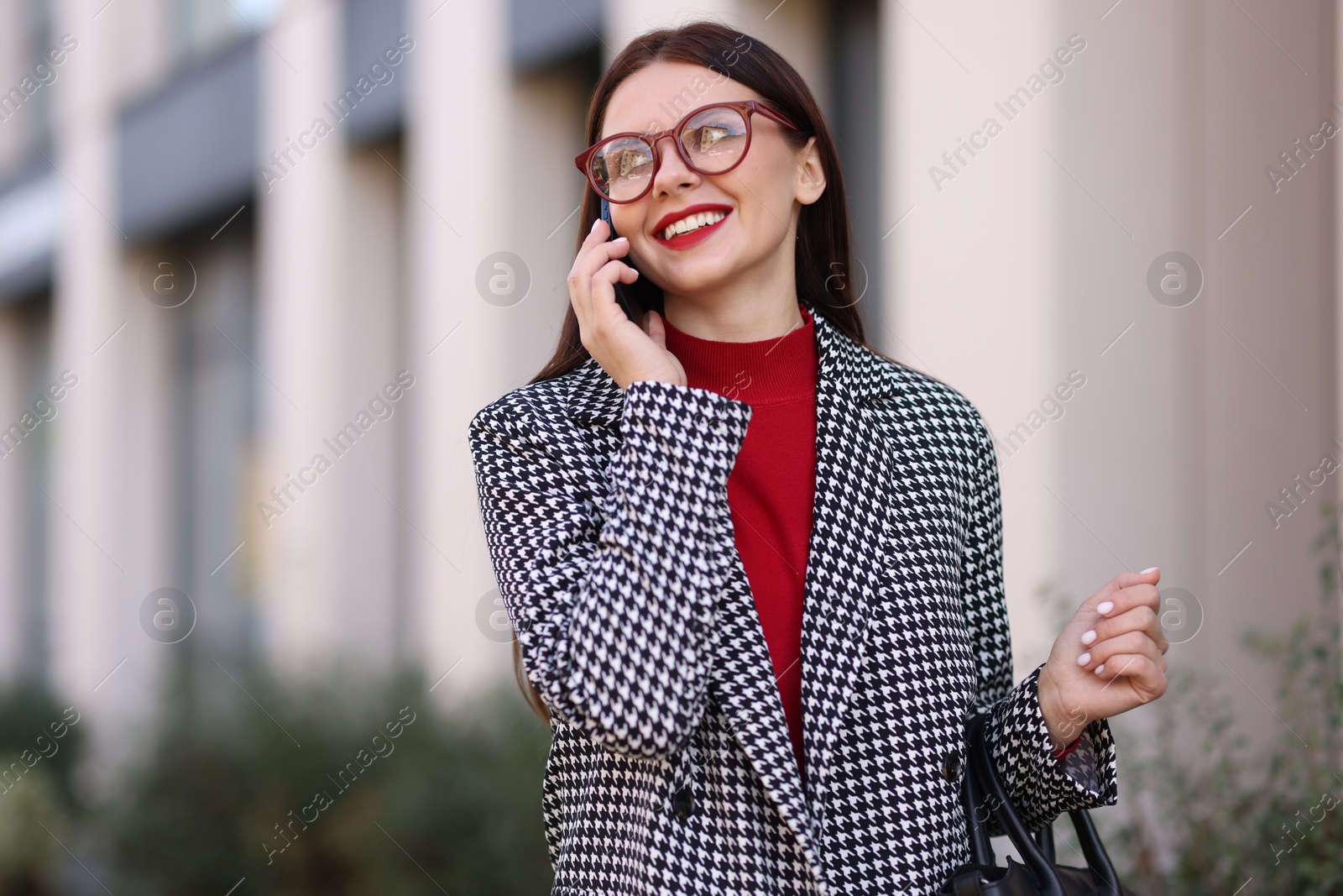 Photo of Beautiful woman in stylish suit talking on smartphone outdoors. Space for text