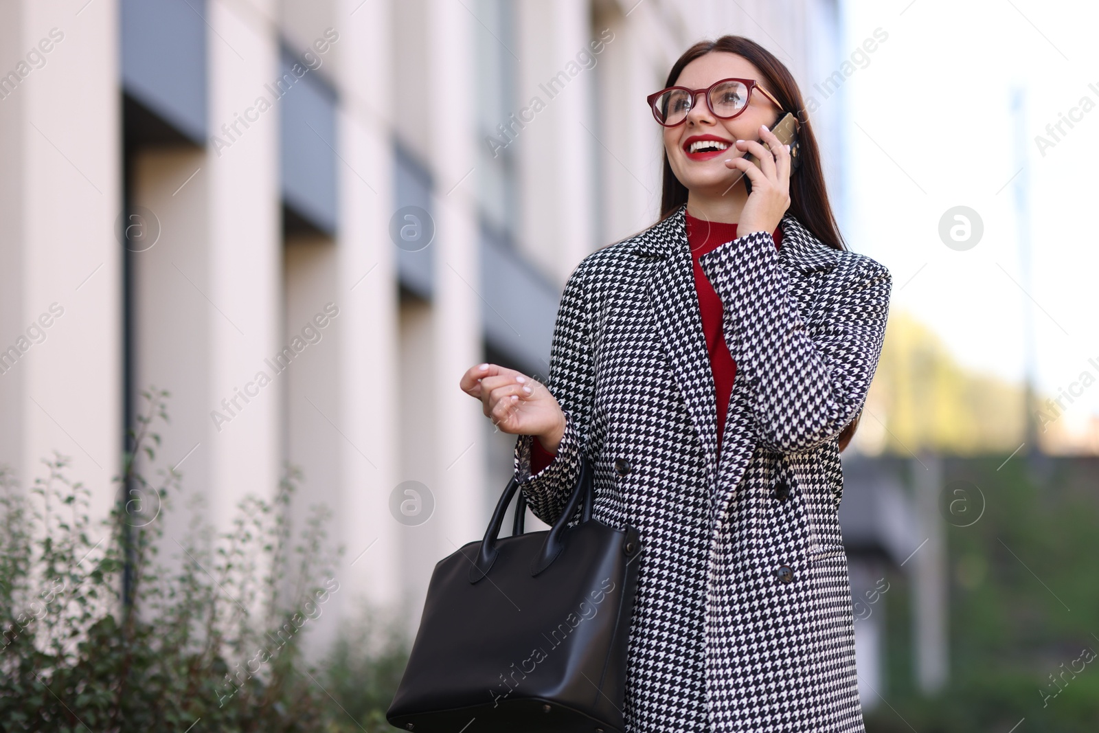 Photo of Beautiful woman in stylish suit talking on smartphone outdoors. Space for text