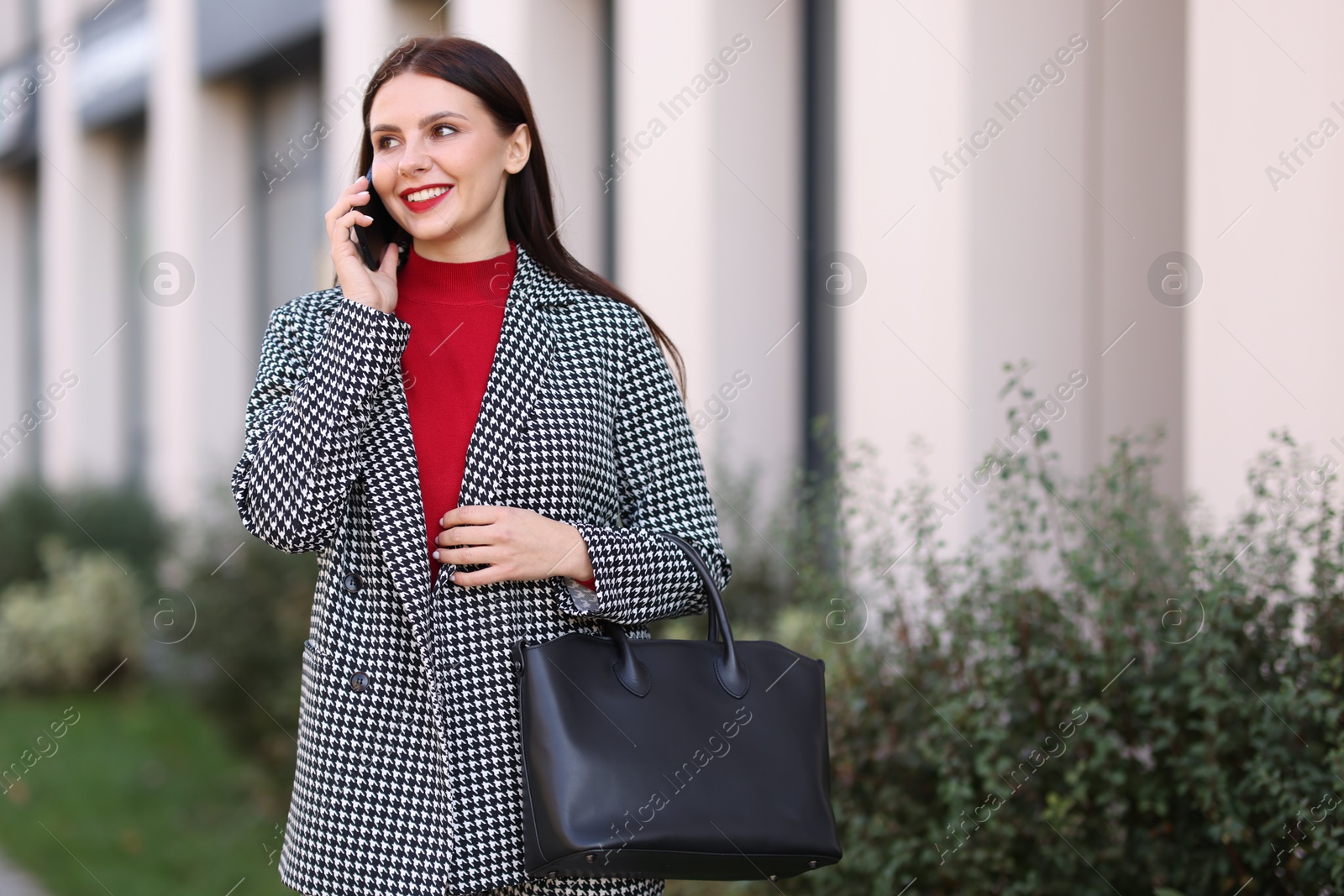 Photo of Beautiful woman in stylish suit talking on smartphone outdoors. Space for text