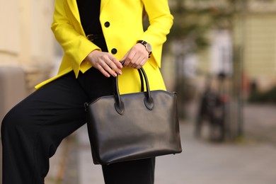 Businesswoman in stylish suit with bag outdoors, closeup. Space for text