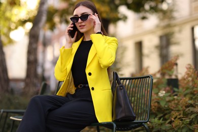 Photo of Businesswoman in stylish suit talking on smartphone outdoors