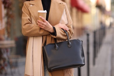 Businesswoman in stylish outfit with paper cup outdoors, closeup