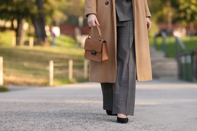 Photo of Businesswoman in stylish suit walking outdoors, closeup. Space for text