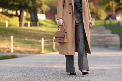 Photo of Businesswoman in stylish suit walking outdoors, closeup. Space for text