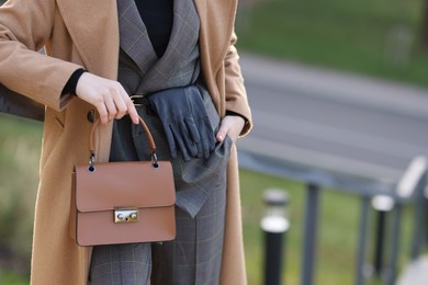 Businesswoman in stylish suit with bag outdoors, closeup. Space for text