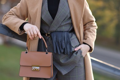 Businesswoman in stylish suit with bag outdoors, closeup view