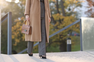 Photo of Businesswoman in stylish suit walking outdoors, closeup. Space for text