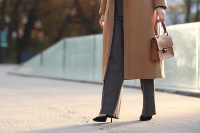 Photo of Businesswoman in stylish suit walking outdoors, closeup. Space for text