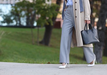 Photo of Businesswoman in stylish suit walking outdoors, closeup. Space for text