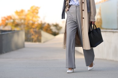 Businesswoman in stylish suit walking outdoors, closeup. Space for text