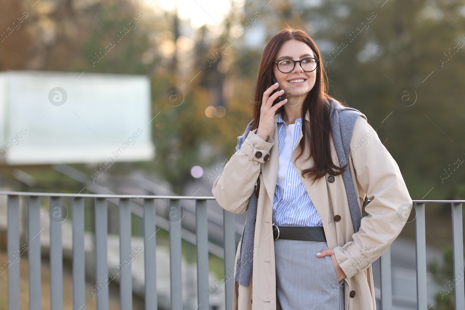 Photo of Beautiful woman in stylish suit talking on smartphone outdoors. Space for text