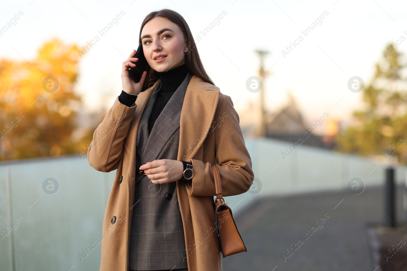 Photo of Businesswoman in stylish suit talking on smartphone outdoors. Space for text