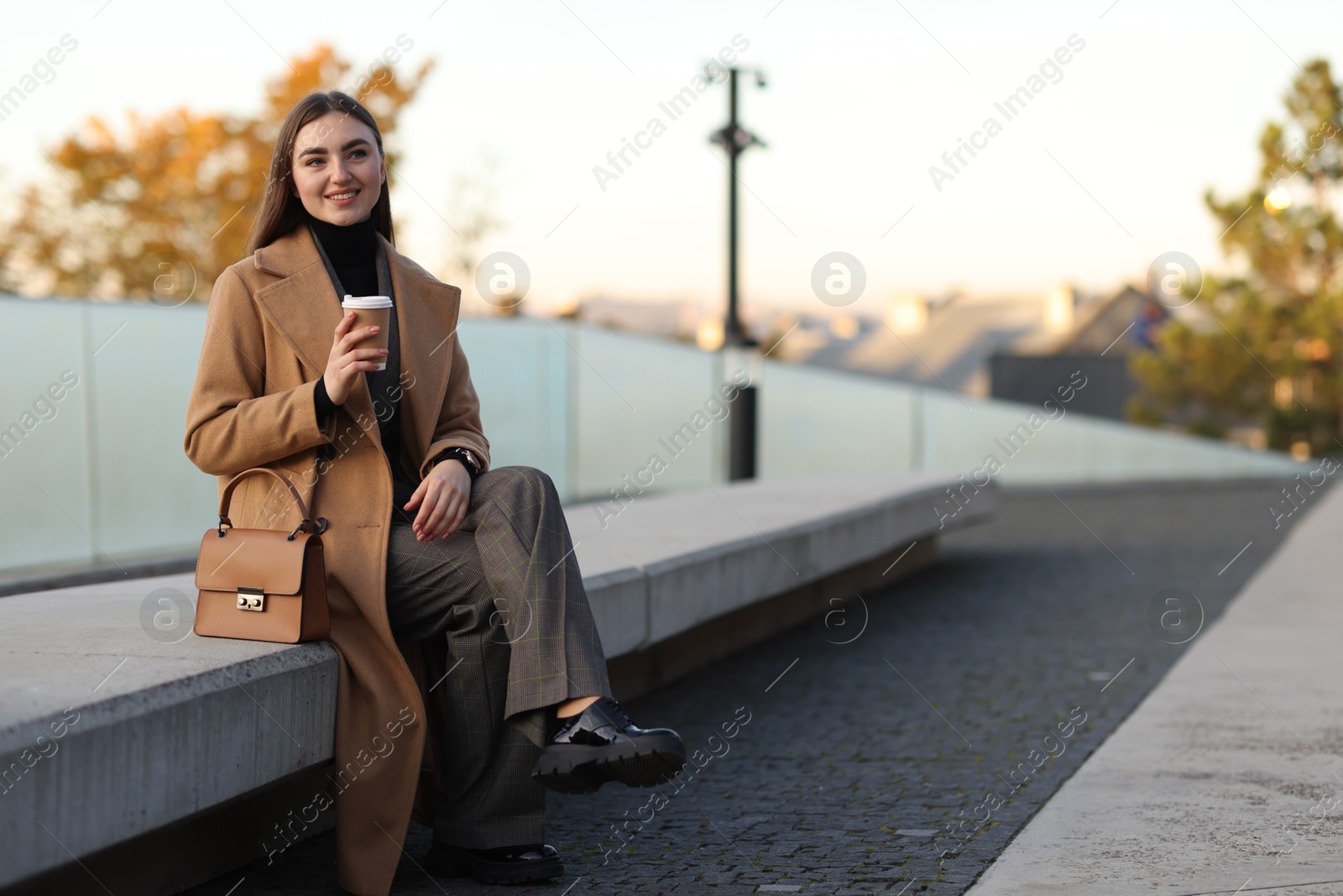 Photo of Beautiful woman in stylish suit with paper cup outdoors. Space for text