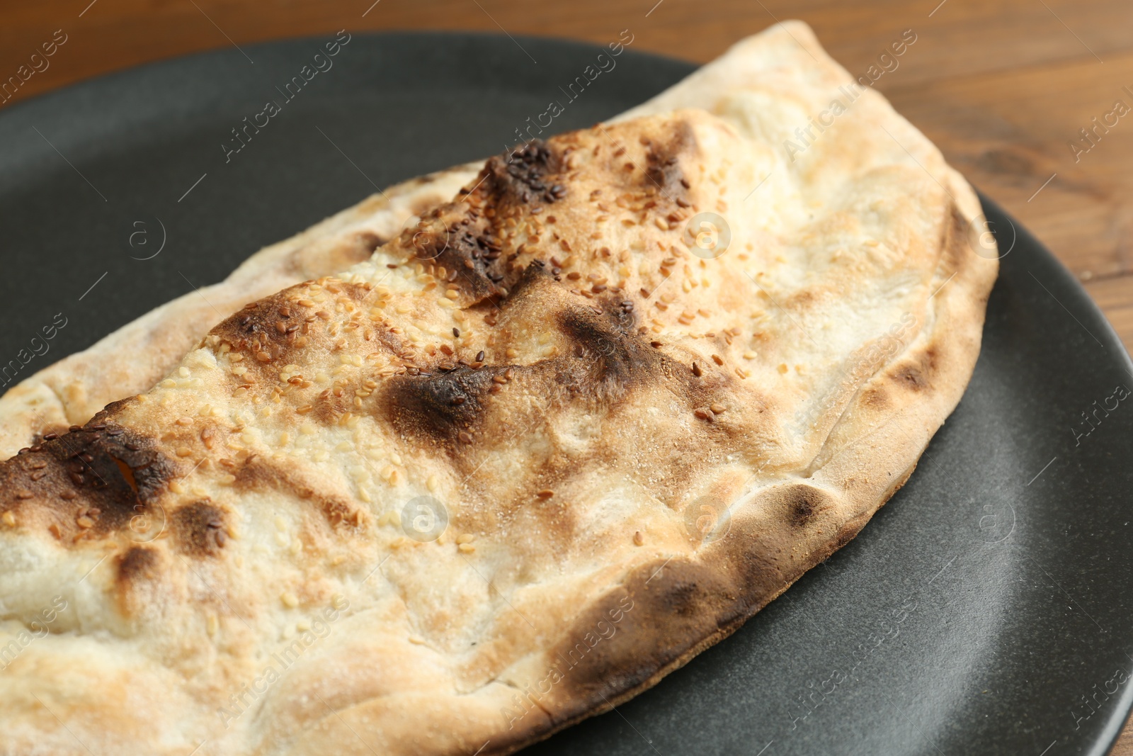 Photo of Plate with tasty calzone on table, closeup