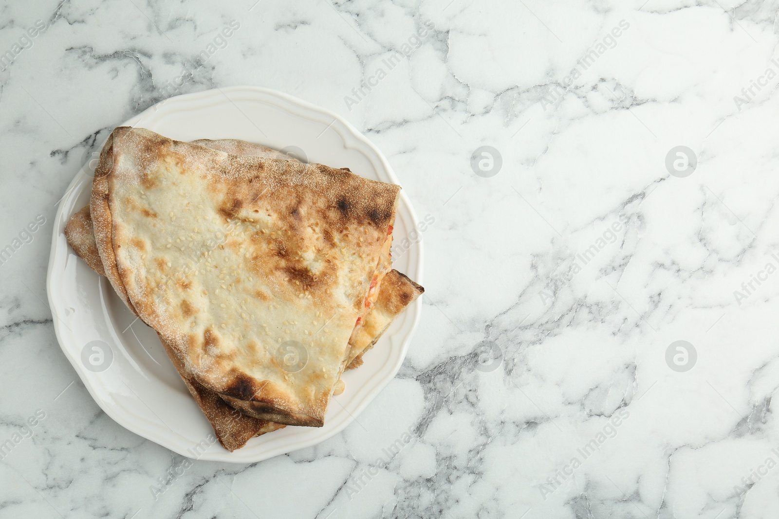 Photo of Halves of tasty calzone on white marble table, top view. Space for text