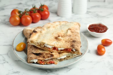 Halves of tasty calzone with meat, cheese, sauce and tomato on white marble table, closeup