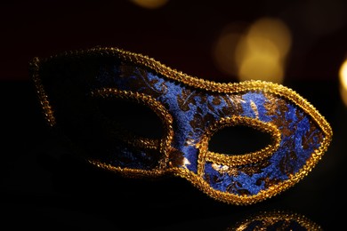 Photo of Beautiful blue carnival mask on black background, closeup. Bokeh effect