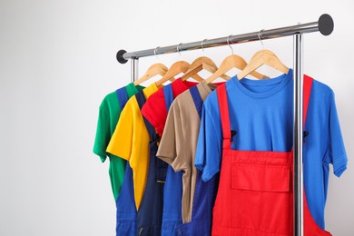 Photo of Workers' uniforms on clothing rack near grey wall indoors