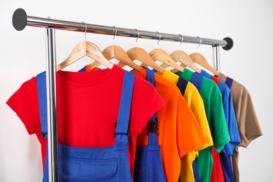 Workers' uniforms on clothing rack near grey wall indoors