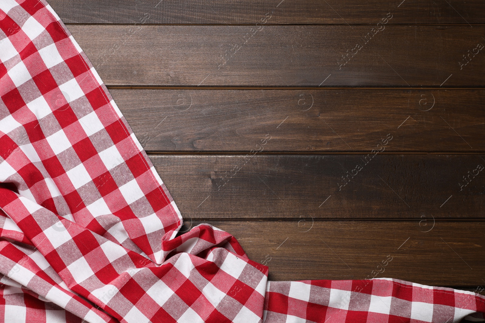 Photo of Crumpled tablecloth with checkered pattern on wooden table, top view. Space for text