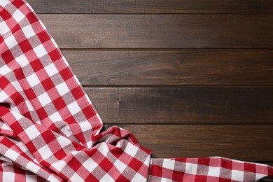 Photo of Crumpled tablecloth with checkered pattern on wooden table, top view. Space for text