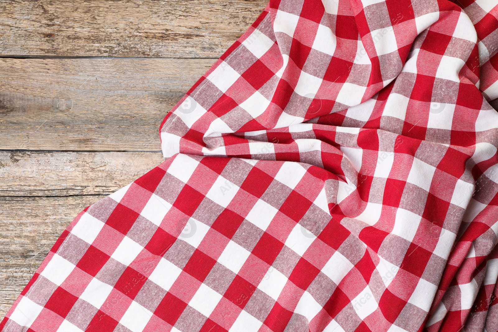 Photo of Crumpled tablecloth with checkered pattern on wooden table, top view