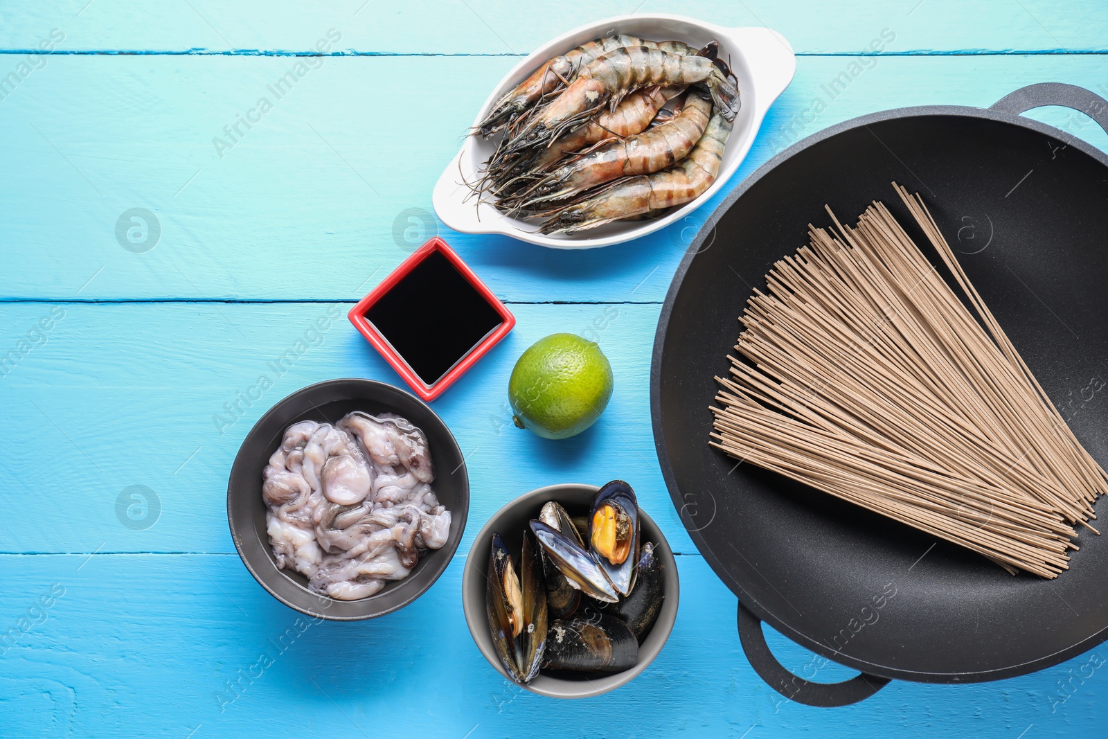 Photo of Different ingredients for wok on light blue wooden table, flat lay