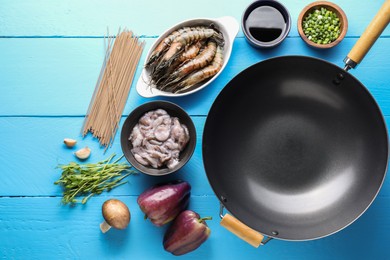 Different ingredients for wok on light blue wooden table, flat lay