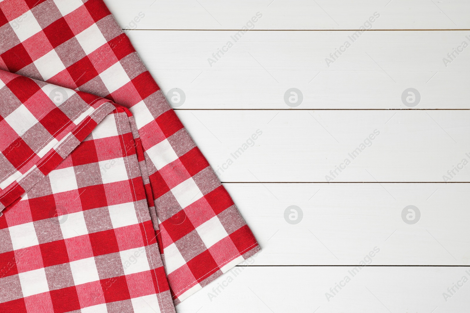 Photo of Folded tablecloth with checkered pattern on white wooden table, top view. Space for text