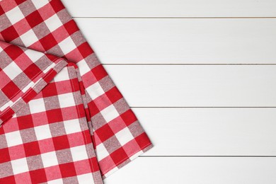 Photo of Folded tablecloth with checkered pattern on white wooden table, top view. Space for text