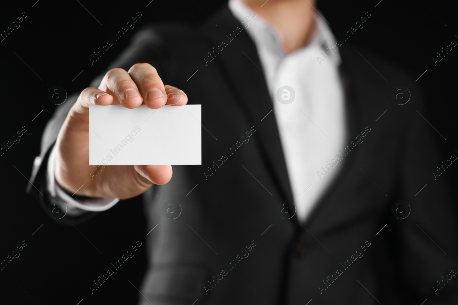 Photo of Man holding blank business card on black background, closeup. Mockup for design