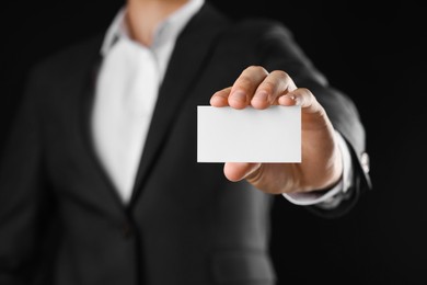 Photo of Man holding blank business card on black background, closeup. Mockup for design