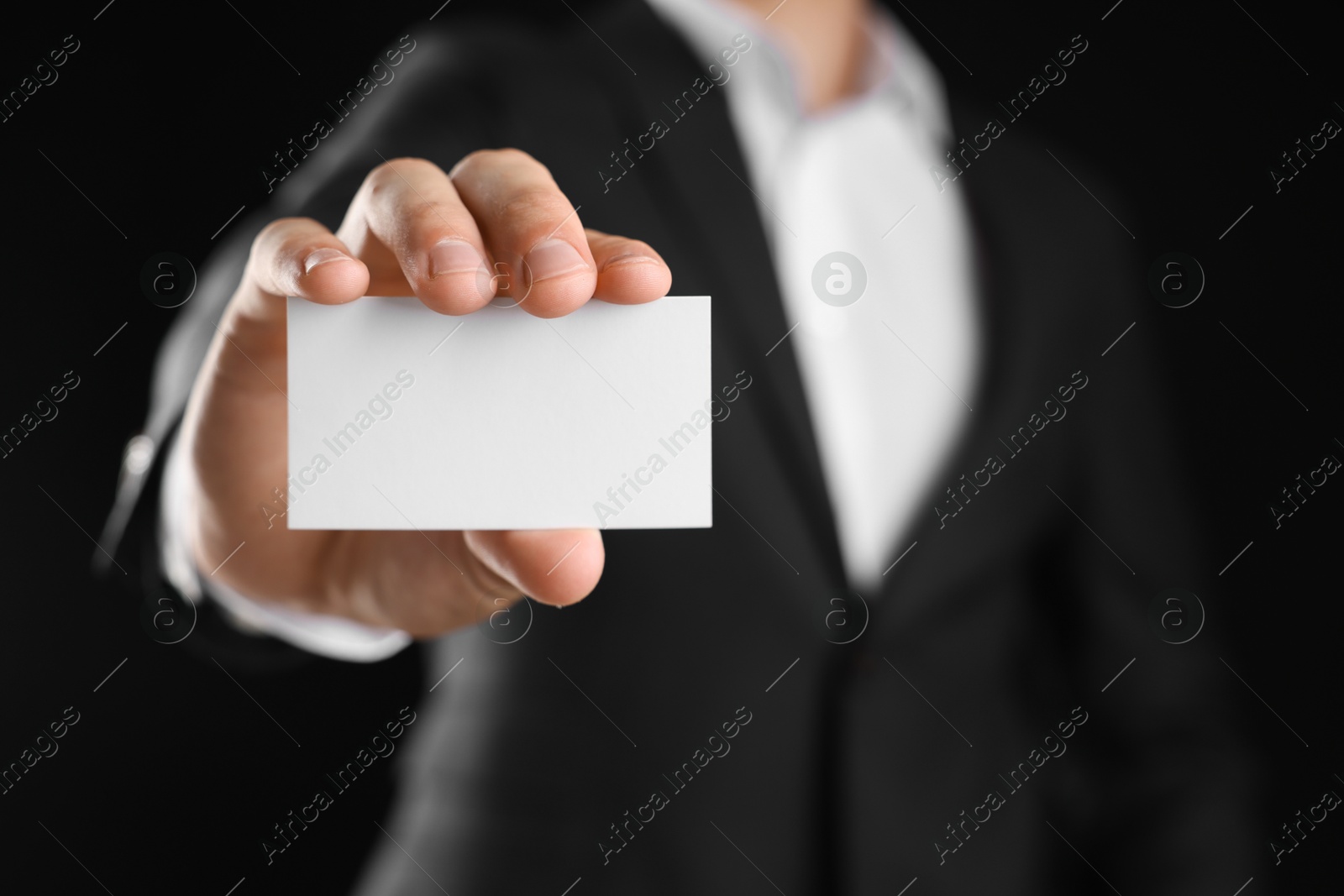 Photo of Man holding blank business card on black background, closeup. Mockup for design