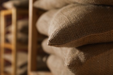 Photo of Group of burlap sacks on shelving unit indoors, closeup. Space for text