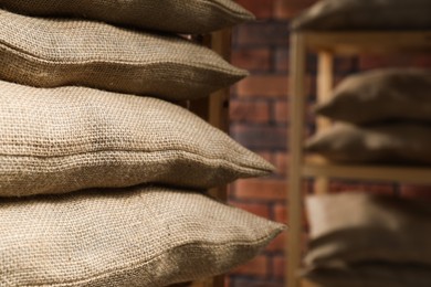 Photo of Group of burlap sacks on shelving unit indoors, closeup. Space for text