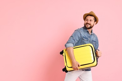 Happy man with suitcase on pink background, space for text