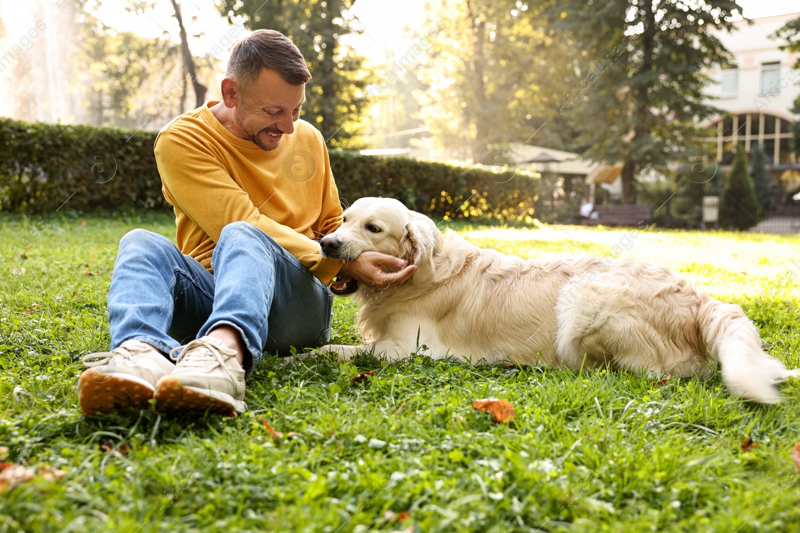 Photo of Smiling man with cute Golden Retriever dog on spring day