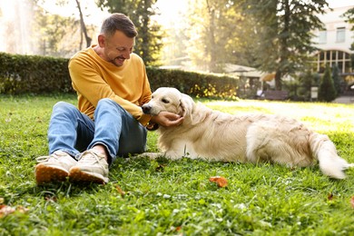 Smiling man with cute Golden Retriever dog on spring day