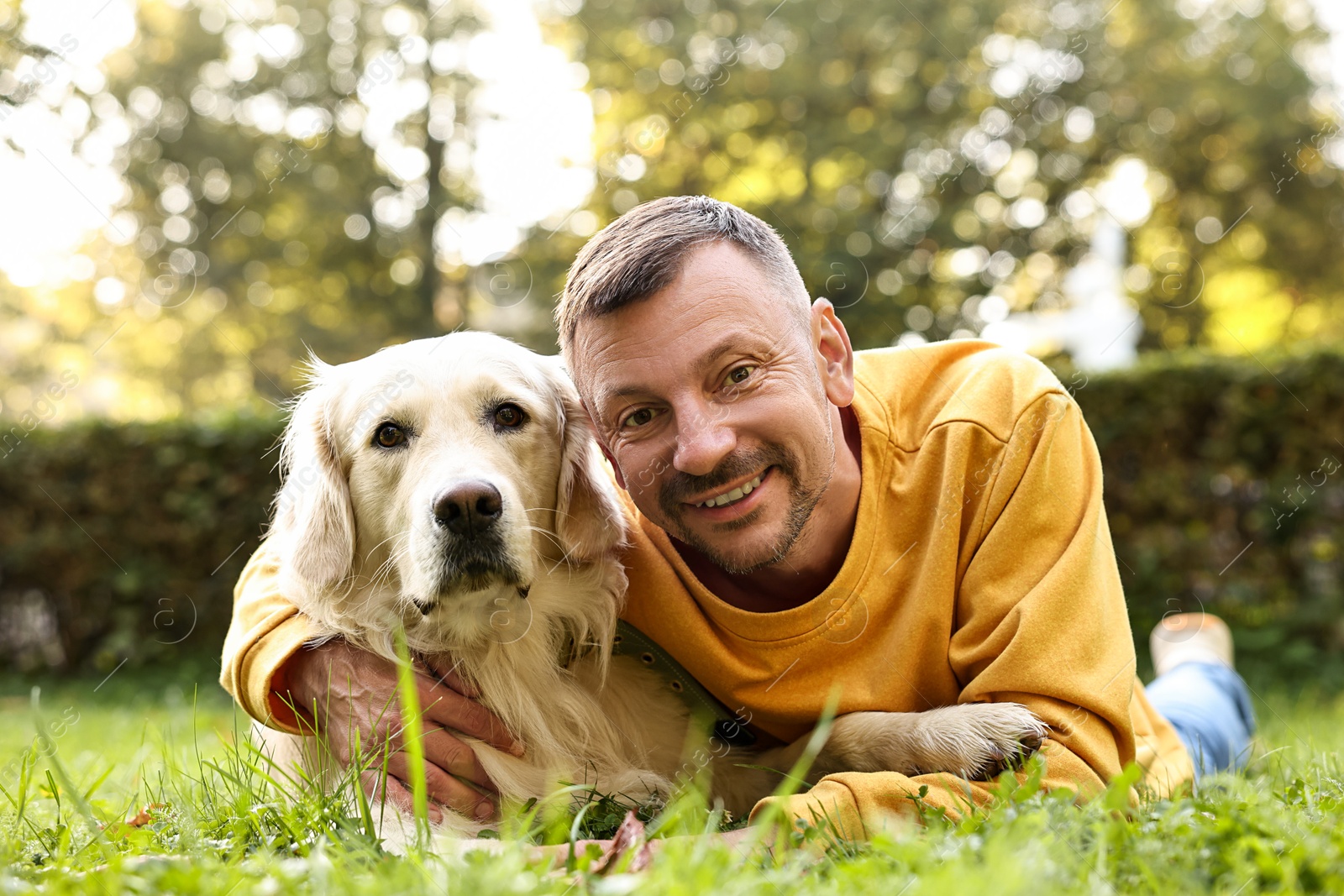 Photo of Smiling man with cute Golden Retriever dog on spring day