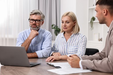 Pension plan. Couple consulting with insurance agent at table indoors