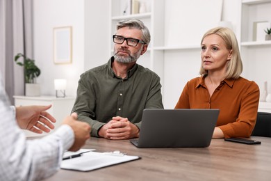 Pension plan. Couple consulting with insurance agent at table indoors