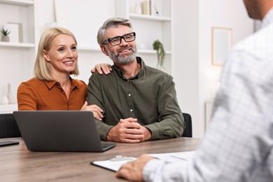 Pension plan. Couple consulting with insurance agent at table indoors