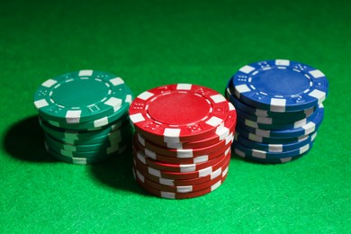 Photo of Stacks of poker chips on green table, closeup