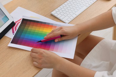 Photo of Designer working with color palette at wooden table, closeup