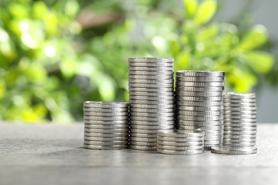 Photo of Salary concept. Stacked coins on grey table against blurred background