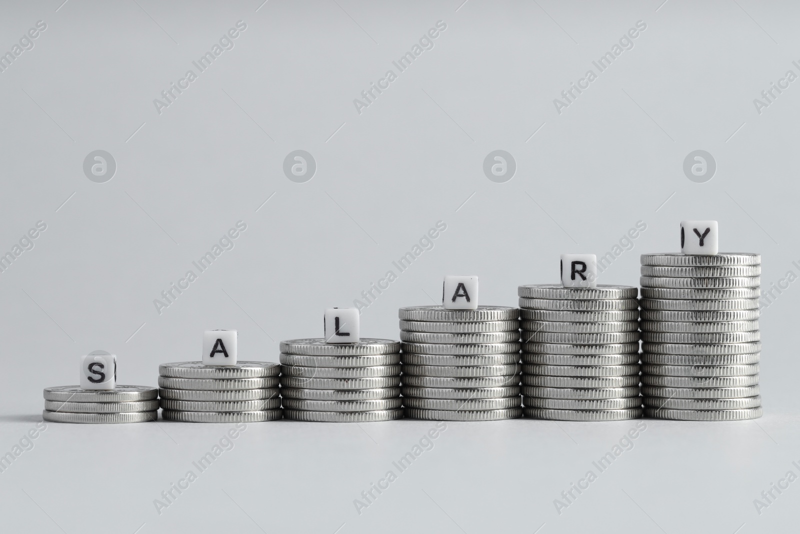 Photo of Word Salary made of cubes and coins on light grey background, space for text