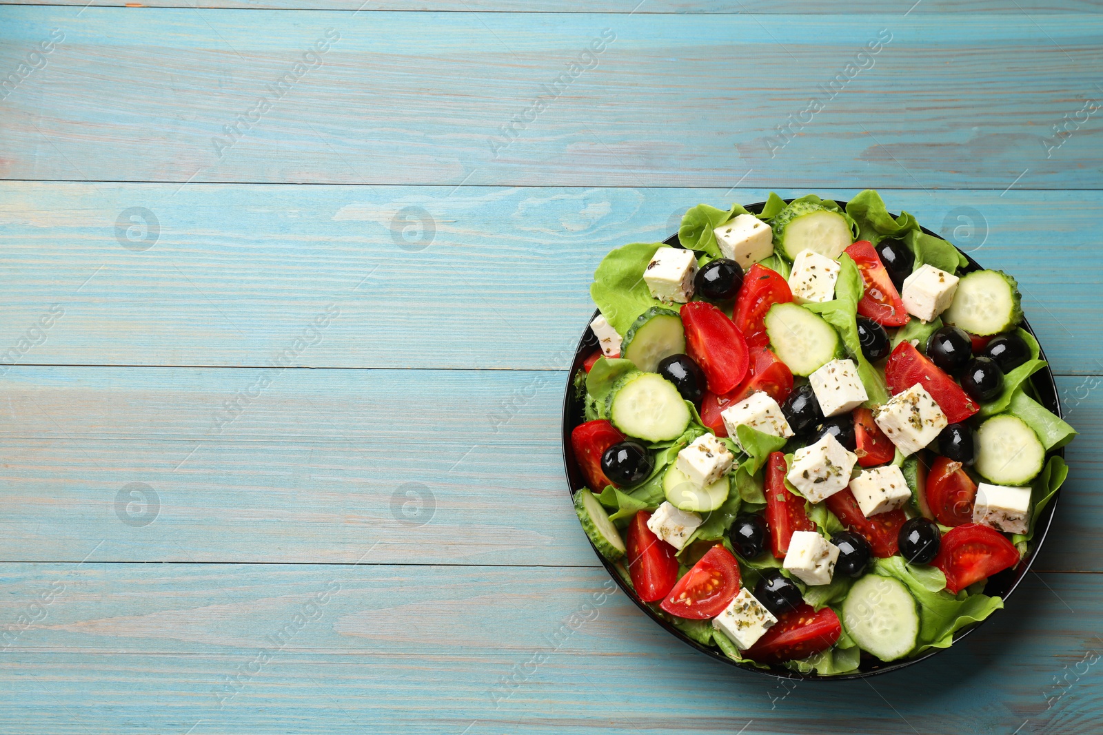 Photo of Delicious salad with feta cheese on light blue wooden table, top view. Space for text