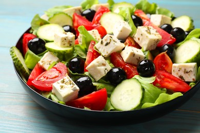 Delicious salad with feta cheese on light blue wooden table, closeup